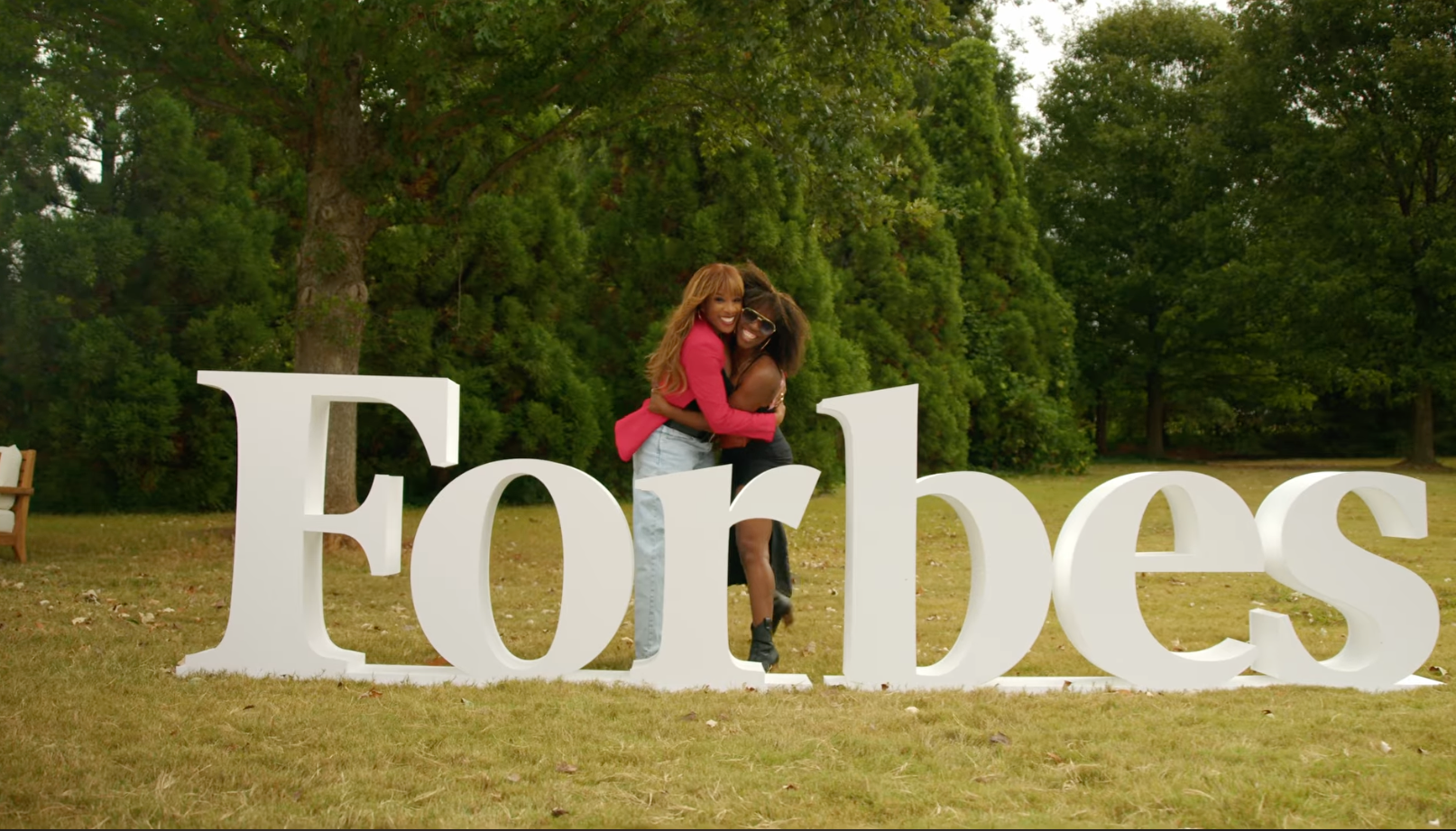 Brittani Mack hugging a friend in front of giant Forbes letters
